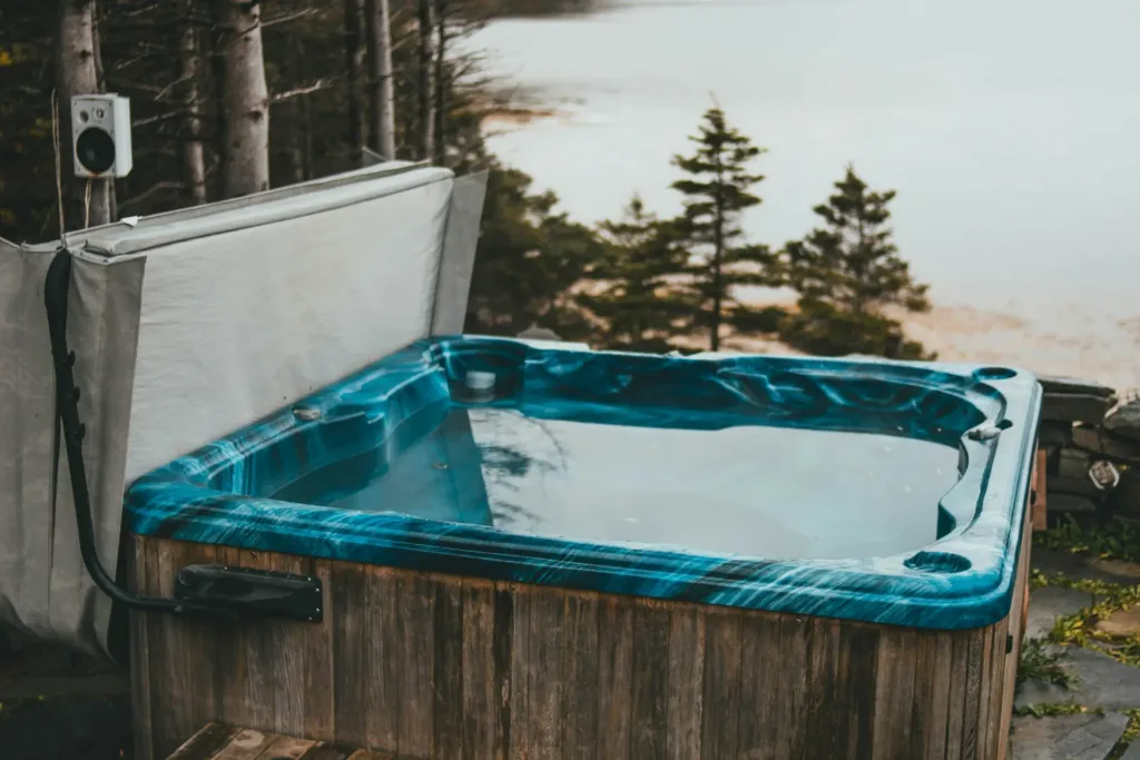 a hot tub and hot tub cover sitting in front of a lake